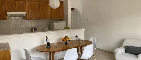 Una cocina moderna con armarios de madera, una mesa de comedor con sillas y un sofá blanco.