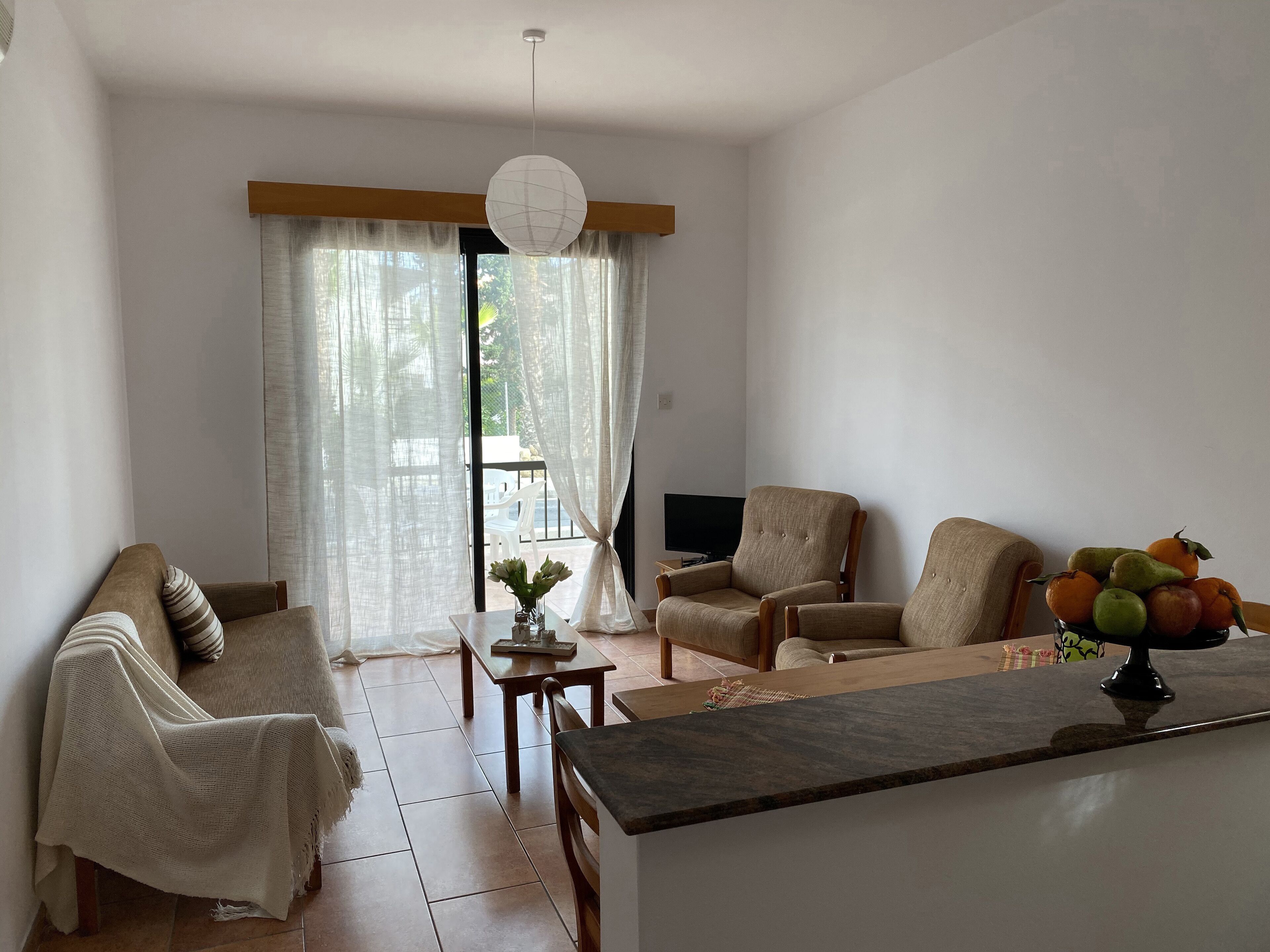 Una sala de estar con un sofá, dos sillones, una mesa de centro y un televisor.