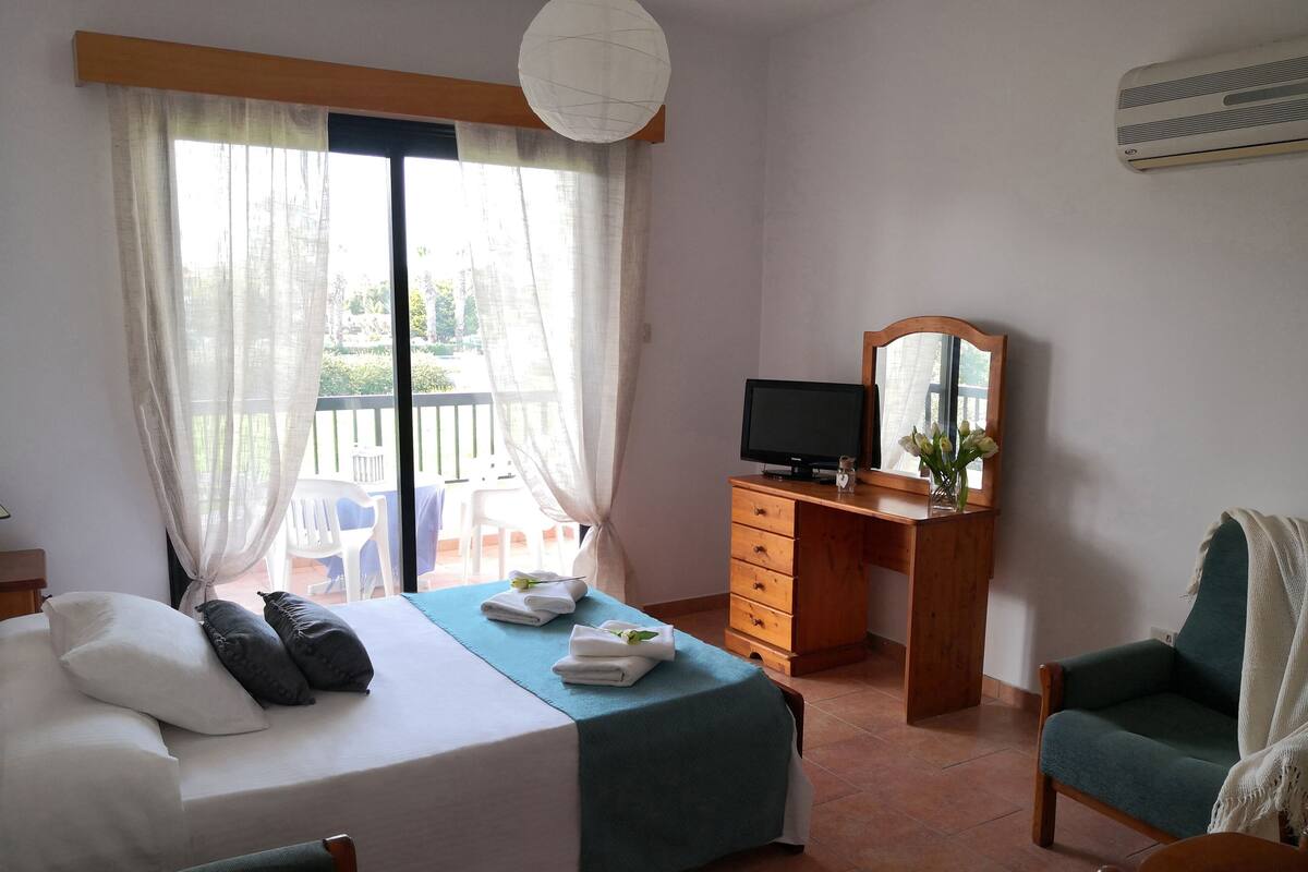 Ein Schlafzimmer mit einem Bett, einem Schreibtisch, einem Sessel und einem Fernseher.