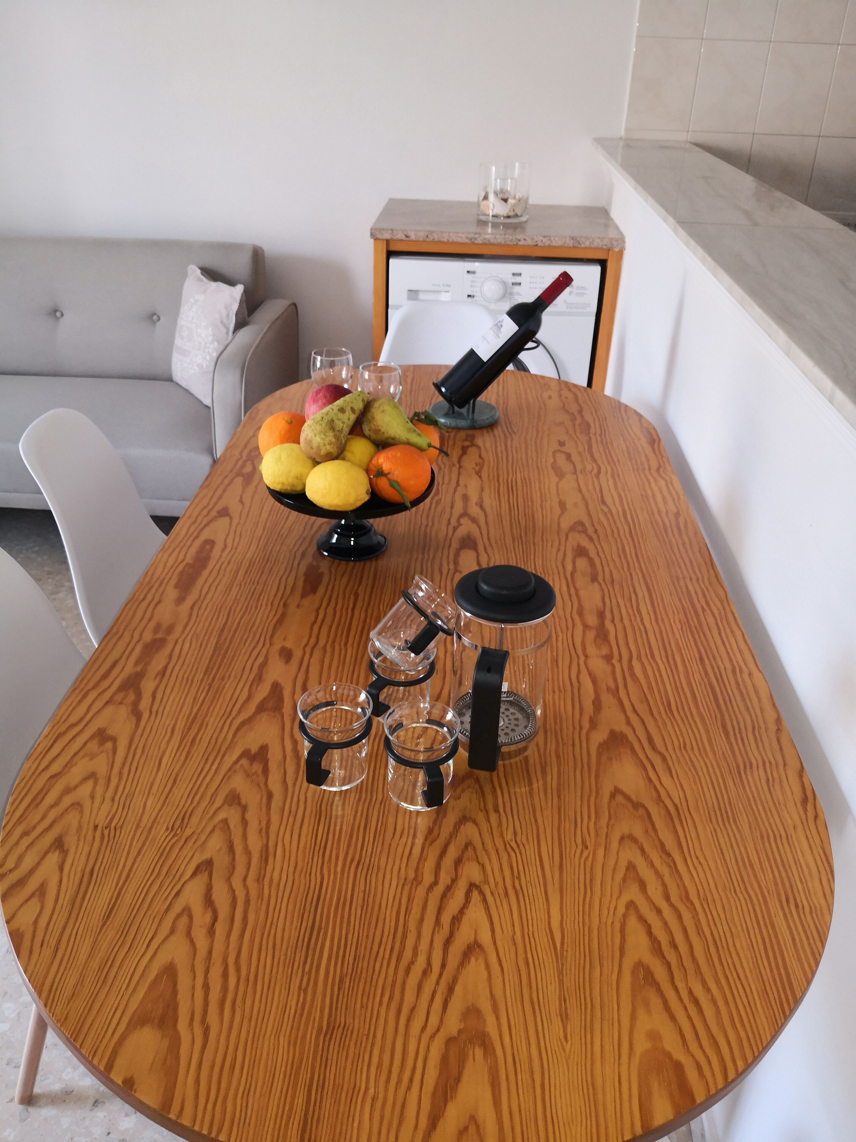 Ett matbord i trä med en fruktskål, en vinflaska och en kaffebryggare.
