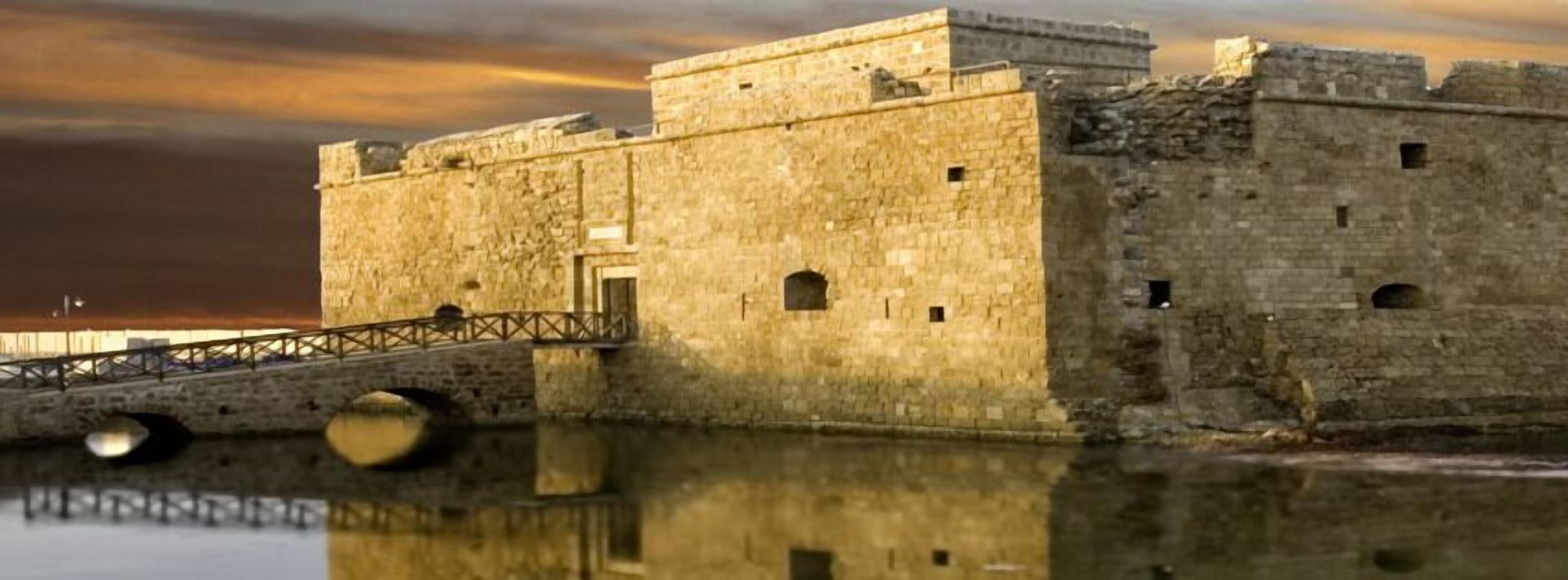 Una fortaleza de piedra con un puente sobre el agua, que refleja la estructura.