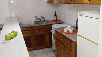 Una cocina con armarios de madera, encimera blanca, fregadero, estufa y refrigerador.