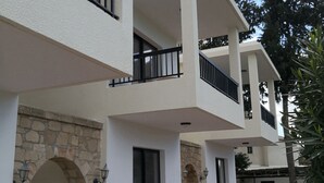 A multi-story residential building with balconies, stone archways, and a tiled patio area. - Seashell Apartments (Paphos)