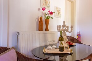 Une table ronde en verre, avec une bouteille, des verres et un plateau de nourriture.