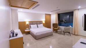 Une chambre d’hôtel avec un grand lit, un bureau, une chaise et une vue sur la piscine.
