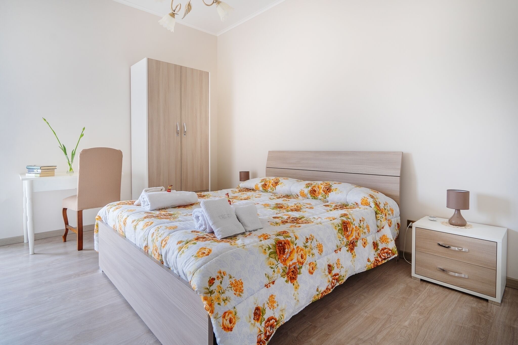 Ein ordentlich eingerichtetes Schlafzimmer mit Bett, Nachttisch, Schrank und Schreibtisch mit Stuhl.