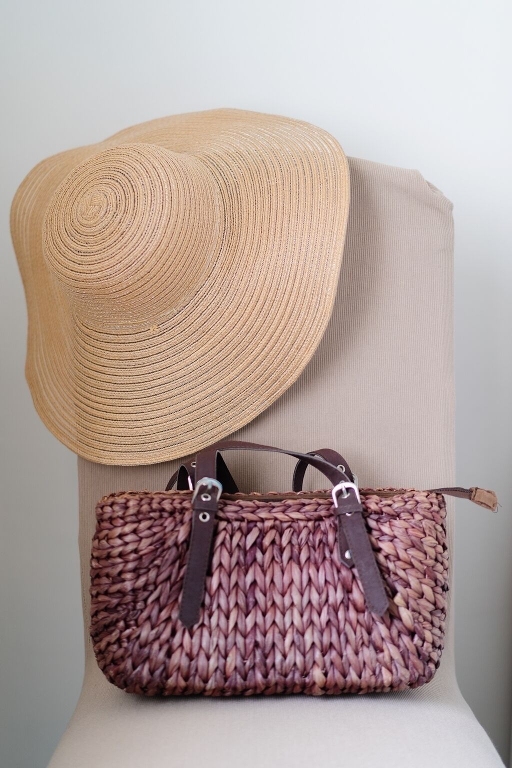 Un mannequin portant un chapeau de paille et un sac à main en osier.