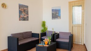 Een gemeubileerde kamer met een zithoek, een klein tafeltje met drankjes en snacks, en twee afbeeldingen in lijsten aan de muur.