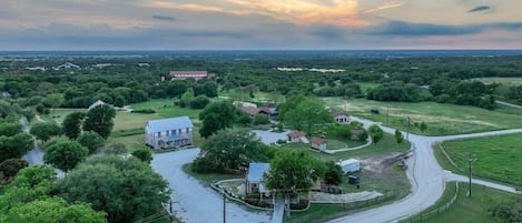 A rural landscape with a winding road, a large white building, and surrounding greenery.