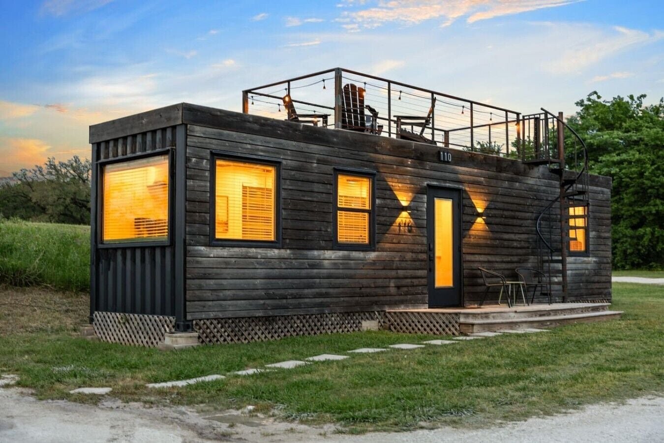 A cabin with a wooden exterior, multiple windows, a door, and a small porch area.