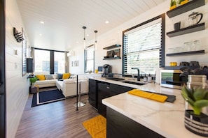 A modern kitchen with a central island, built-in appliances, and a large window providing natural light.
