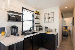 A modern kitchen with black cabinets, a built-in dishwasher, and a coffee machine.