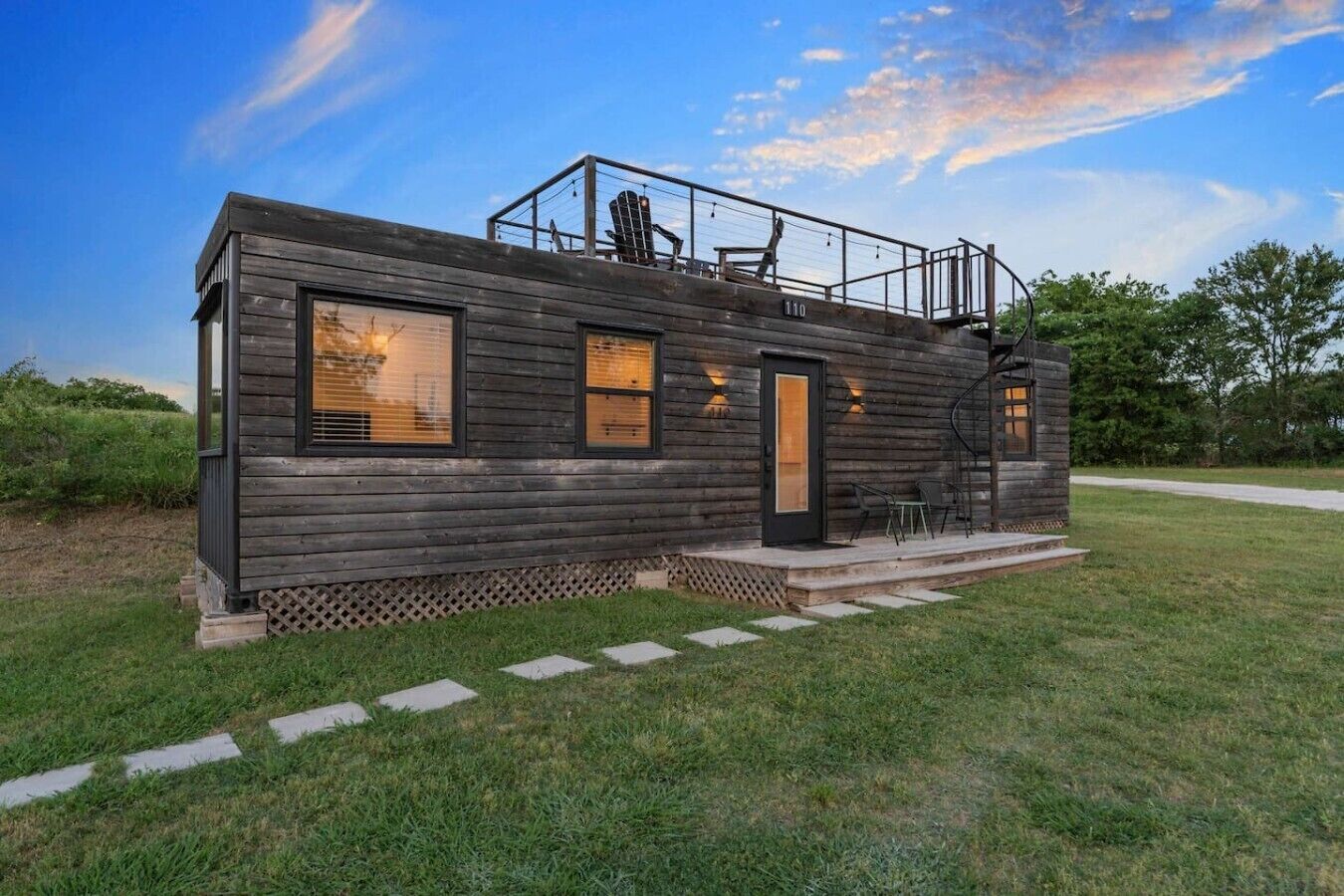 Eine Blockhütte mit Balkon, Tür und einer kleinen Sitzgelegenheit im Freien.