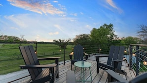 A deck with outdoor seating and a view of a green field. - Container home with rooftop views and pickleball (Waco)