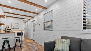 A modern interior with a kitchen, dining area, and a living room with a sofa and a window. - Container home with rooftop views and pickleball (Waco)