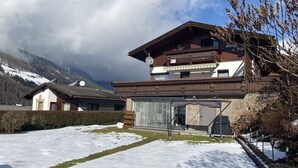 Eine zweistöckige Chalet mit Holzbalkon und Steinverkleidung, vor einer Berglandschaft gelegen.