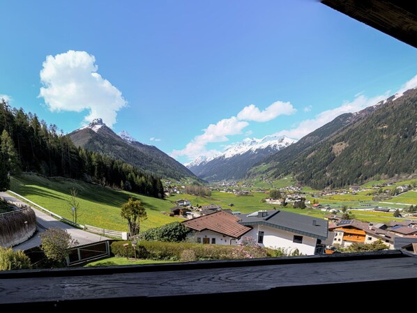 A mountainous landscape with a village, houses with sloped roofs, and a clear sky.