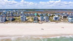 A coastal residential area with beachfront properties, including multi-story buildings with balconies and a sandy beach. - 8 Bedroom Direct Oceanfront Home, Private Pool, Media Room, Private Beach Access, 2025 Updates (North Topsail Beach)