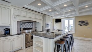 A spacious kitchen with white cabinetry, a granite countertop, and a large island with bar stools. - 8 Bedroom Direct Oceanfront Home, Private Pool, Media Room, Private Beach Access, 2025 Updates (North Topsail Beach)