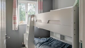 A bunk bed with a lower bunk, a window with curtains, and a radiator on the wall. - Modern 4 Bedroom Detached House in Cardiff (Cardiff)