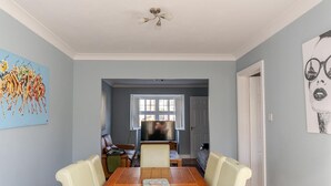 A dining area with a wooden table and chairs, a window with blinds, and a ceiling fan. - Modern 4 Bedroom Detached House in Cardiff (Cardiff)