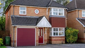 A two-story residential building with a red garage door, a brick facade, and a pitched roof. - Modern 4 Bedroom Detached House in Cardiff (Cardiff)