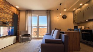 A modern living room with a sofa, a TV, and a kitchen area with cabinets and a microwave. - BP Apartment I (Torun)