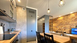 A modern kitchen with a wooden countertop, a built-in oven, and a dining area with a wooden table and chairs. - BP Apartment I (Torun)