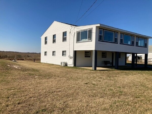 A modern two-story house with a flat roof, large windows, and a covered porch area. - Prime Hook Retreat - Amazing View of the Refuge - Beach Access Across the Street (Milford)