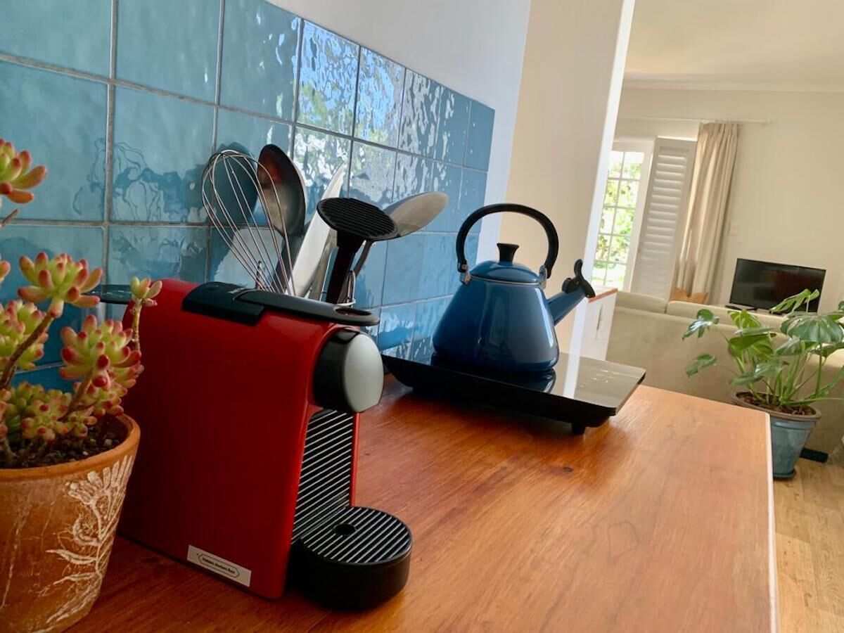 A kitchen with a red appliance, a blue kettle, and various utensils on the counter.
