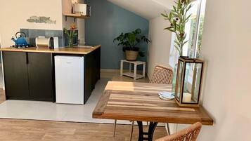 A modern kitchen with a dining area, a potted plant, and a view of the outdoors.