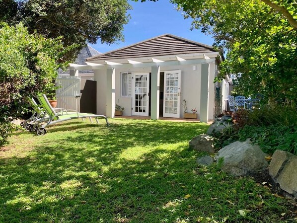 A house with a covered porch, a lawn, and a garden with rocks and plants.
