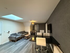Un apartamento moderno con tragaluz, sofá, mesa de comedor y zona de bar.