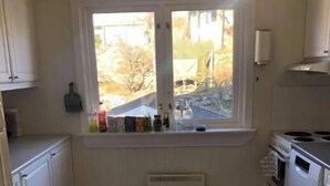 A small kitchen with a window, white cabinets, a built-in oven, and a radiator. - StayPlus Central Five Bedroom Home (Kristiansand)