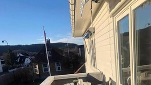 Una terraza de madera con una mesa y sillas, una bandera y vistas a casas al fondo.