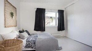 A bedroom with a bed, a window with curtains, a radiator, and a wall-mounted plant. - StayPlus Central Five Bedroom Home (Kristiansand)