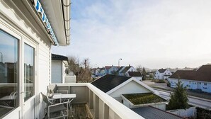A balcony with a table and chairs, overlooking a residential area with houses and a street. - StayPlus Central Five Bedroom Home (Kristiansand)
