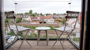 A balcony with two chairs and a small table, overlooking a residential area with houses and a train track. - 8 Deben Wharf, Woodbridge (Woodbridge)