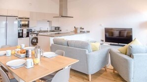 A modern kitchen with a dining area, a sofa, and a TV. - 8 Deben Wharf, Woodbridge (Woodbridge)