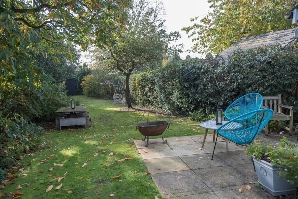 A patio with a table and chairs, a hanging chair, and a fire pit.