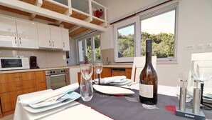Une cuisine moderne avec des meubles blancs, une table à manger dressée avec des assiettes, des verres et une bouteille de vin.