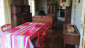 Un comedor con una mesa dispuesta para cuatro, chimenea y un amplio armario de madera.