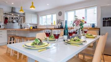 A modern kitchen with white cabinets, a dining table set for four with plates, glasses, and a vase of flowers.