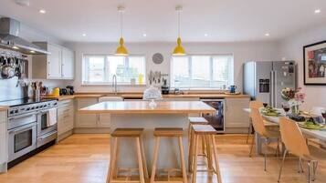 A modern kitchen with wooden stools, a central island, and stainless steel appliances.