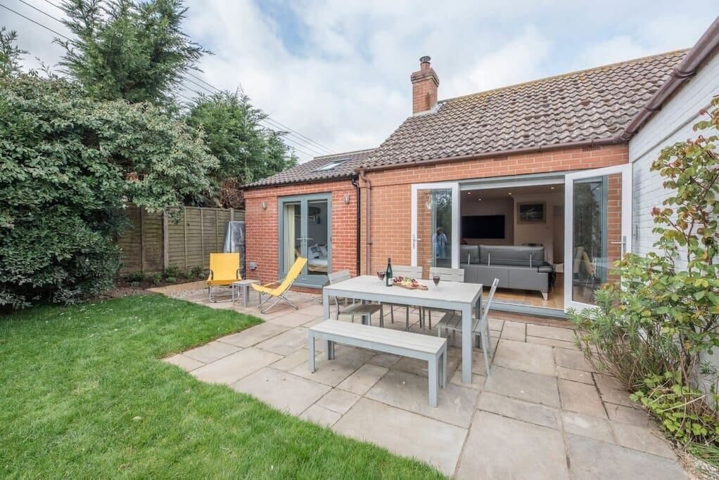 Een huis met een terras, een eettafel en een gele stoel.