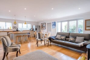 A spacious living area with a sofa, chairs, and a dining table. - Honey Bee House, Orford (Orford)