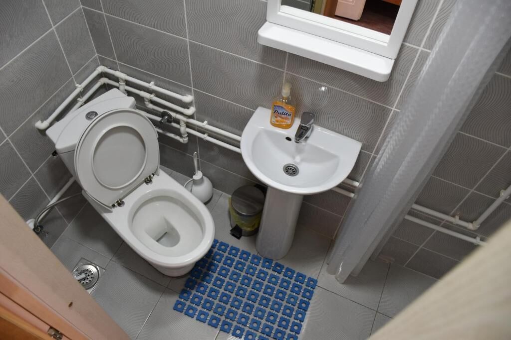 A bathroom with a toilet, sink, and a blue mat on the floor.
