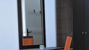 Una habitación con escritorio, silla, armario y espejo.