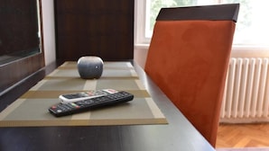 Un control remoto sobre un tapete junto a una silla con un cojín.