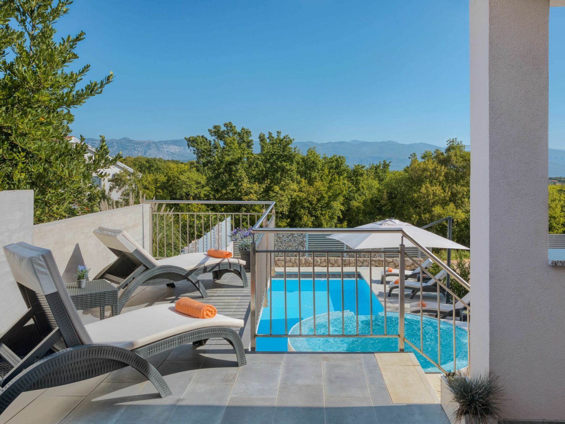 A pool area with lounge chairs and a view of mountains.